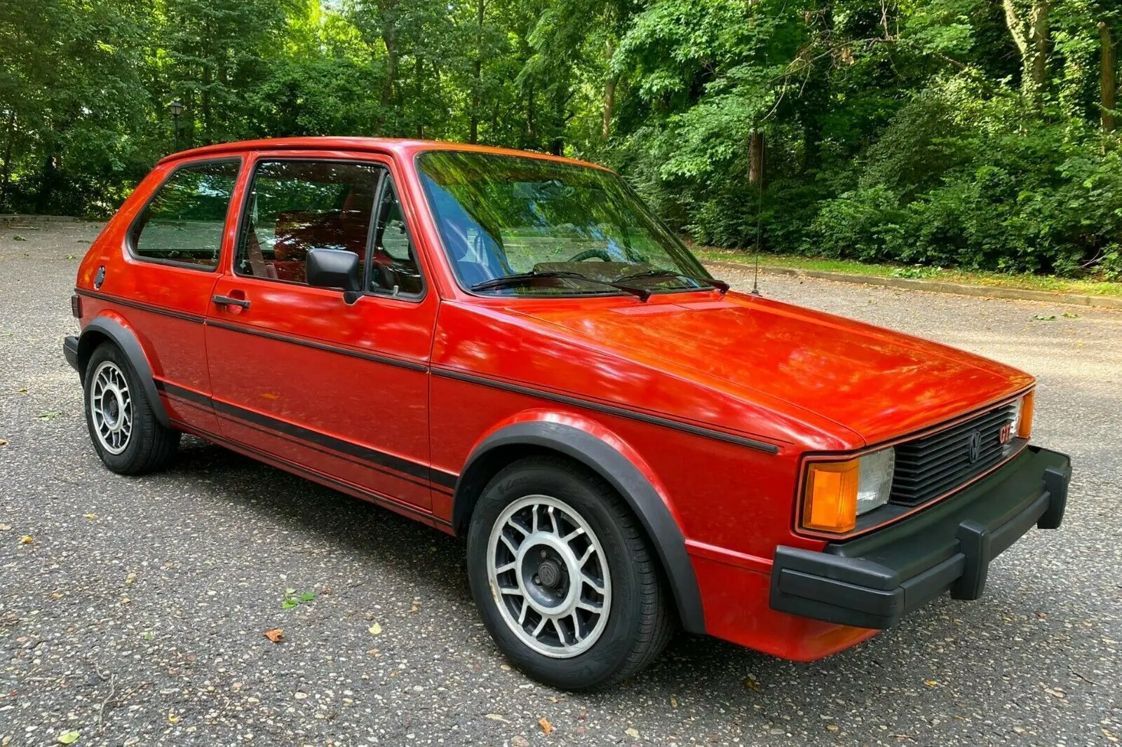 Red Volkswagen GTI parked on asphalt.