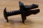 Black plastic push-type fastener on wood.